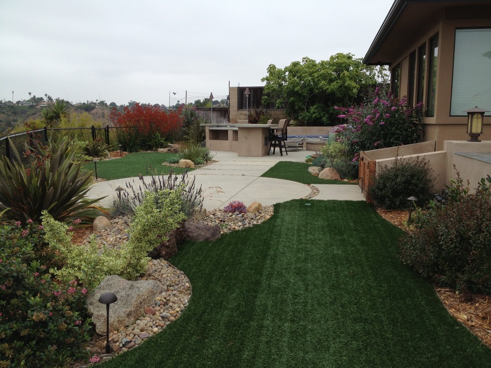 This is an example of a large modern full sun backyard concrete paver and metal fence landscaping in San Diego for summer.