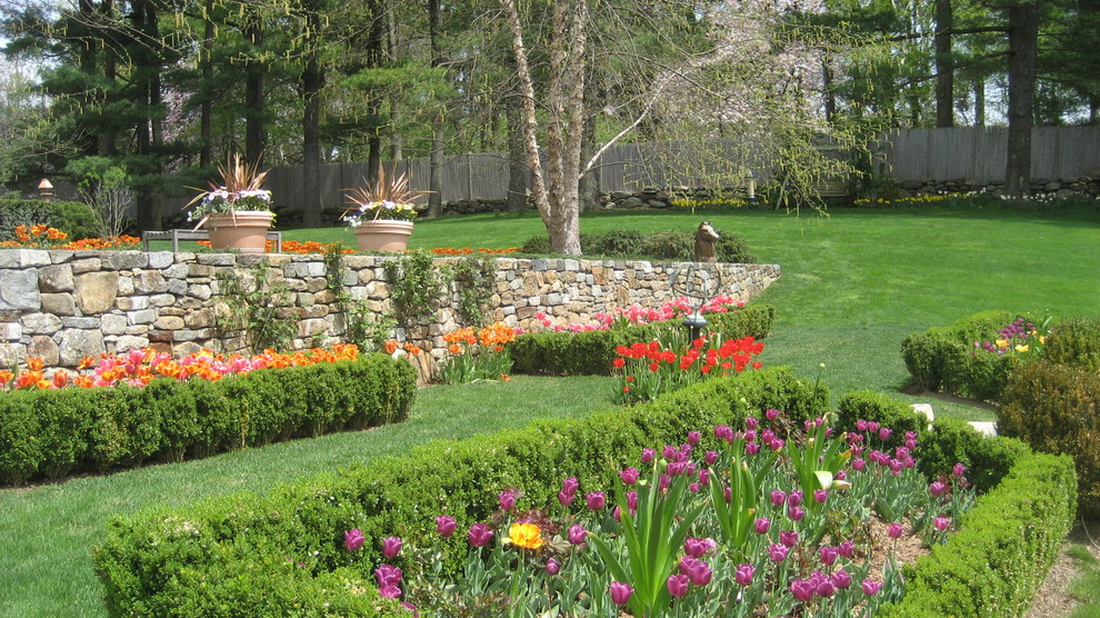 Idee per un ampio giardino formale contemporaneo esposto in pieno sole dietro casa in primavera con un muro di contenimento