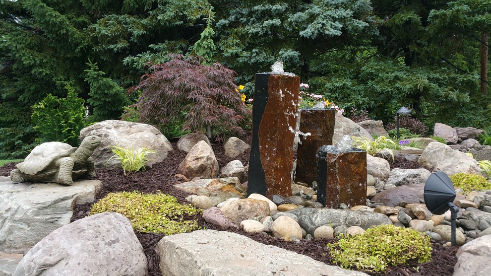 Modelo de jardín rústico en patio trasero con jardín francés, fuente y gravilla