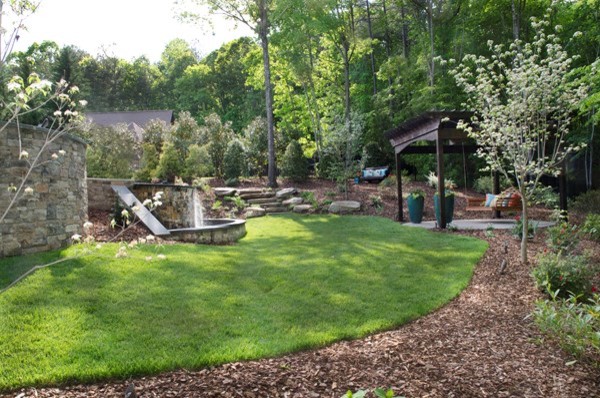 На фото: большой садовый фонтан на заднем дворе в классическом стиле с полуденной тенью и покрытием из каменной брусчатки