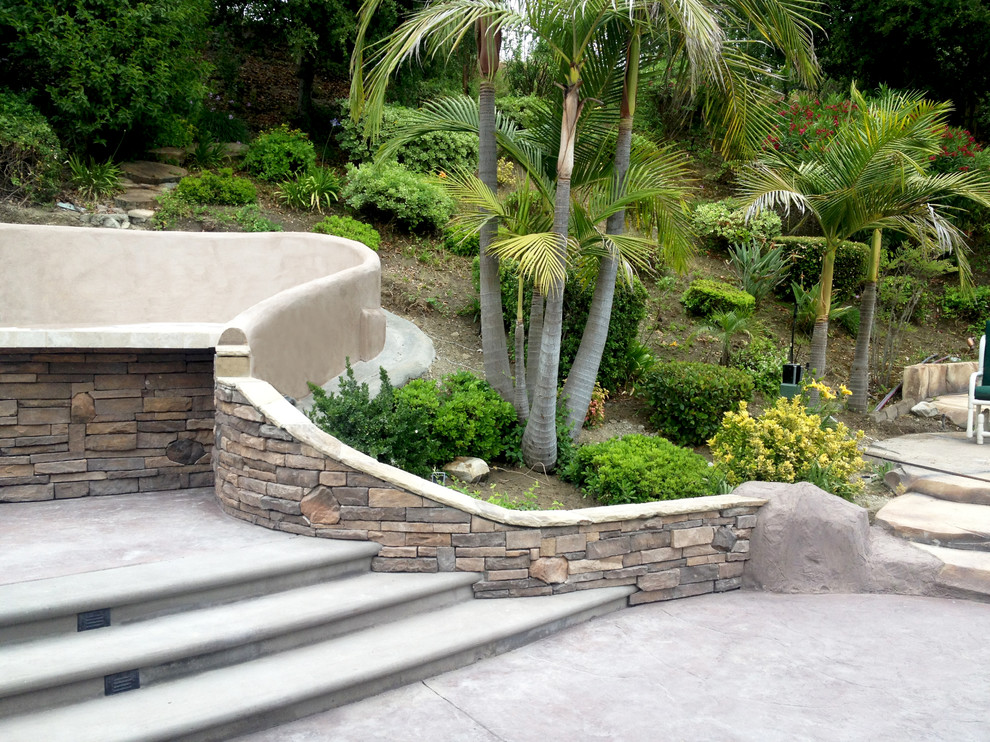 Medium sized mediterranean back full sun garden in Los Angeles with a retaining wall and concrete paving.