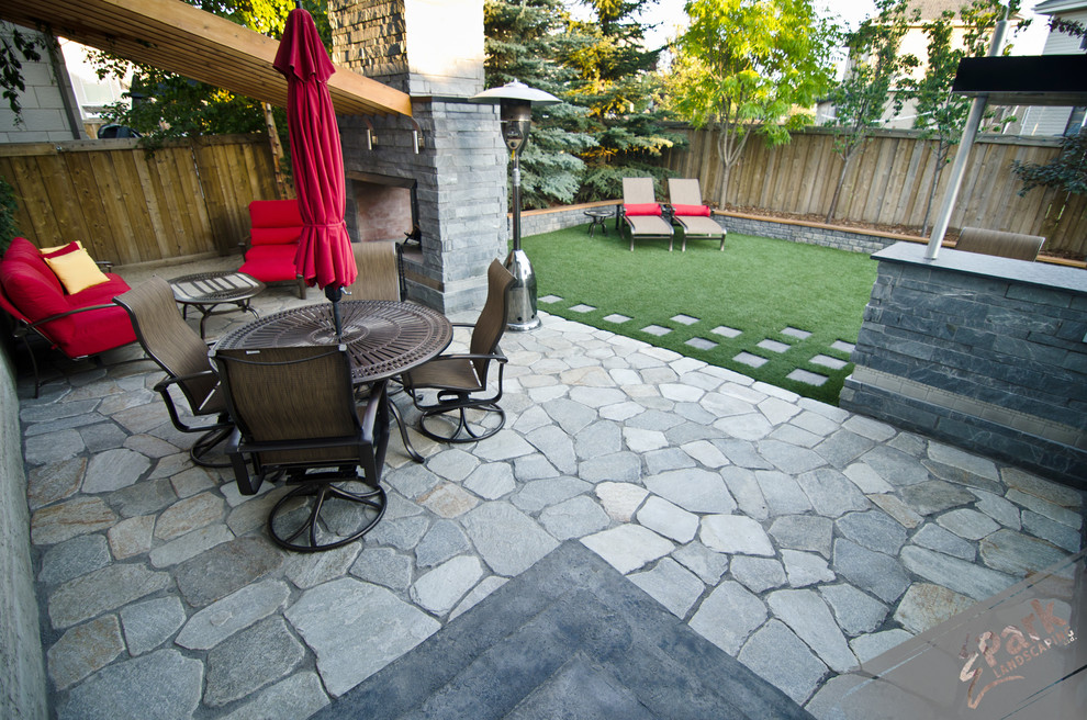 Idee per un grande patio o portico minimal dietro casa con un focolare e pavimentazioni in pietra naturale
