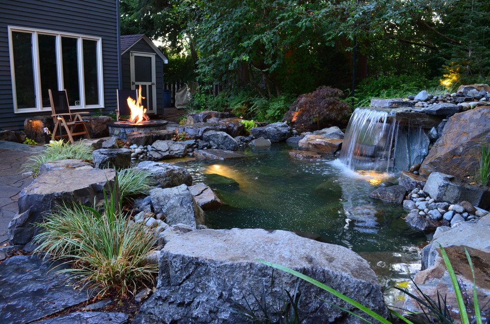 Uriger Gartenwasserfall hinter dem Haus mit Flusssteinen in Seattle