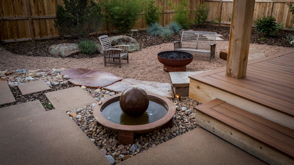 This is an example of a mid-sized drought-tolerant and full sun backyard gravel landscaping in Denver with a fire pit for summer.