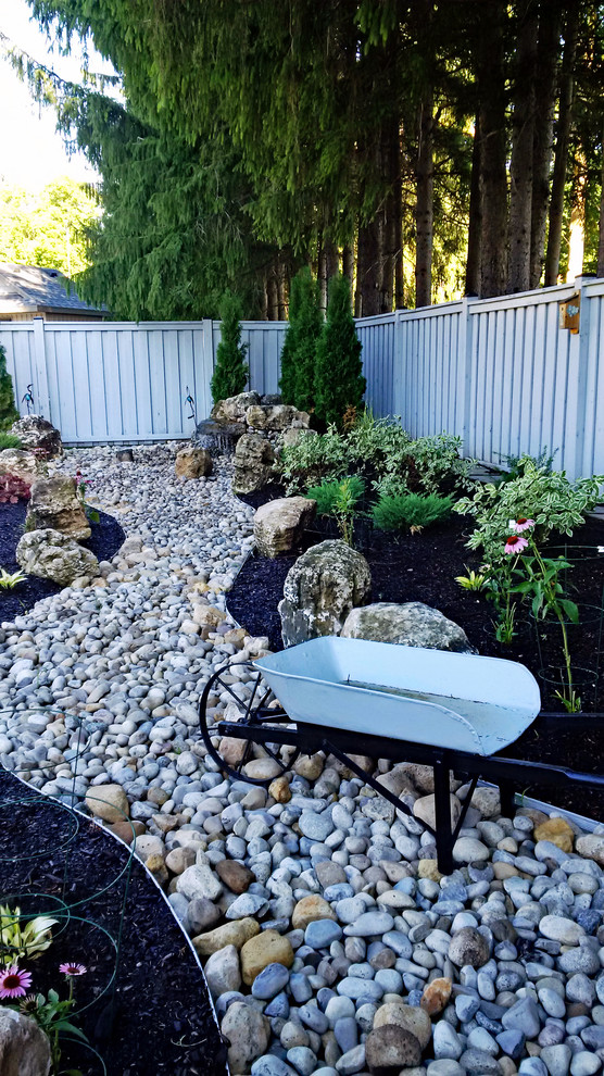 Design ideas for a mid-sized traditional partial sun backyard river rock landscaping in Toronto for summer.
