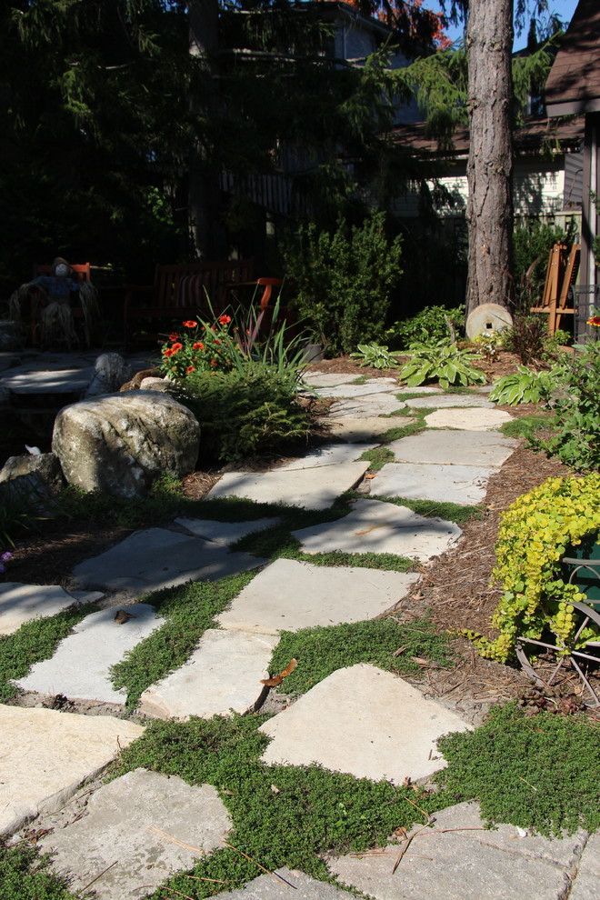 Medium sized rustic back partial sun garden for spring in Toronto with a water feature and natural stone paving.