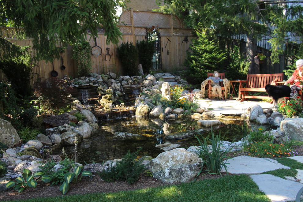 Design ideas for a mid-sized rustic partial sun backyard stone water fountain landscape in Toronto for spring.