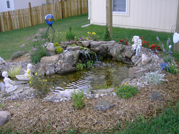 Foto di un giardino tradizionale esposto a mezz'ombra dietro casa in estate con fontane e pavimentazioni in pietra naturale