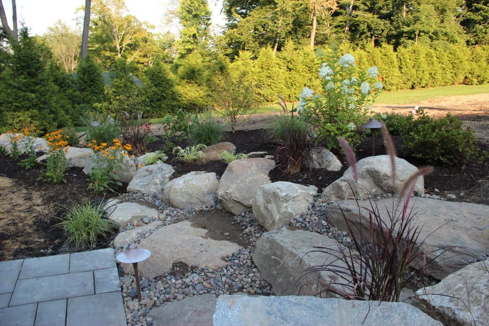 Photo of a medium sized classic back xeriscape partial sun garden for spring in New York with concrete paving and a retaining wall.