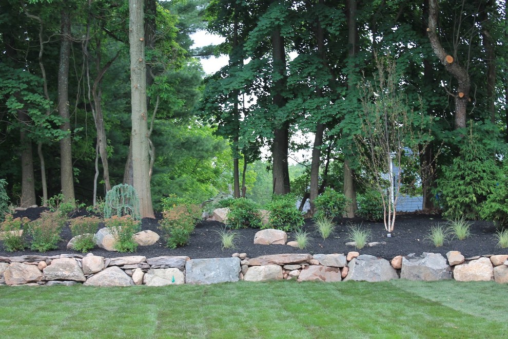 Immagine di un grande giardino tradizionale esposto a mezz'ombra dietro casa con un muro di contenimento e pavimentazioni in cemento