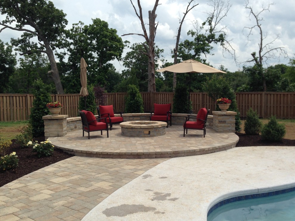Ejemplo de jardín de estilo americano de tamaño medio en patio trasero con brasero, exposición total al sol y adoquines de piedra natural