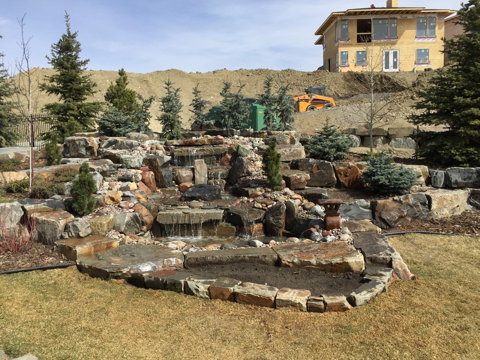Photo of a mid-sized modern partial sun backyard stone landscaping in Calgary.