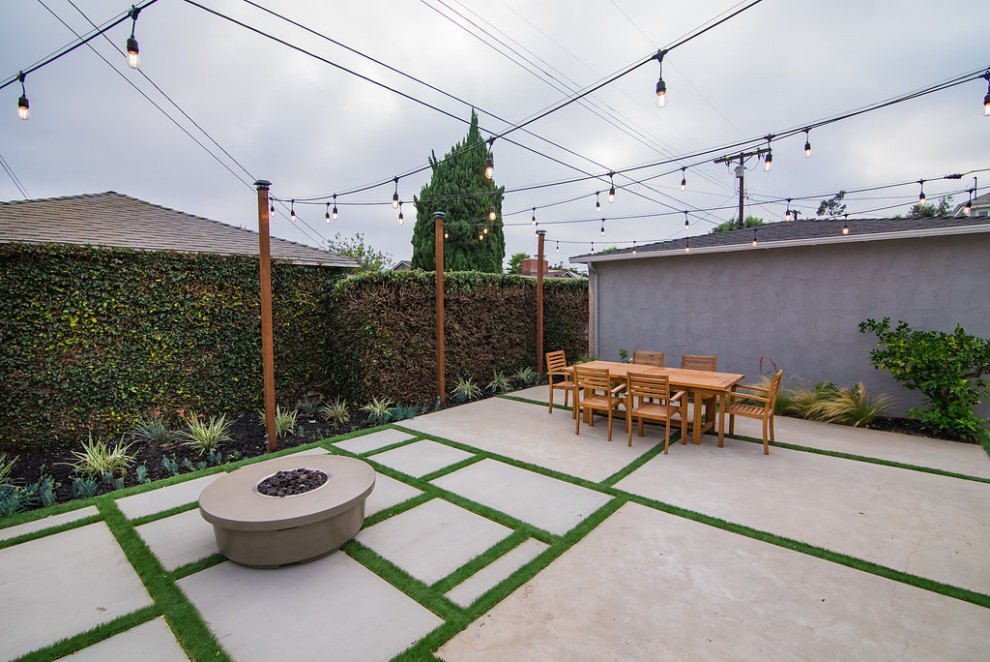 На фото: маленький весенний регулярный сад на заднем дворе в современном стиле с местом для костра, полуденной тенью и мощением тротуарной плиткой для на участке и в саду с