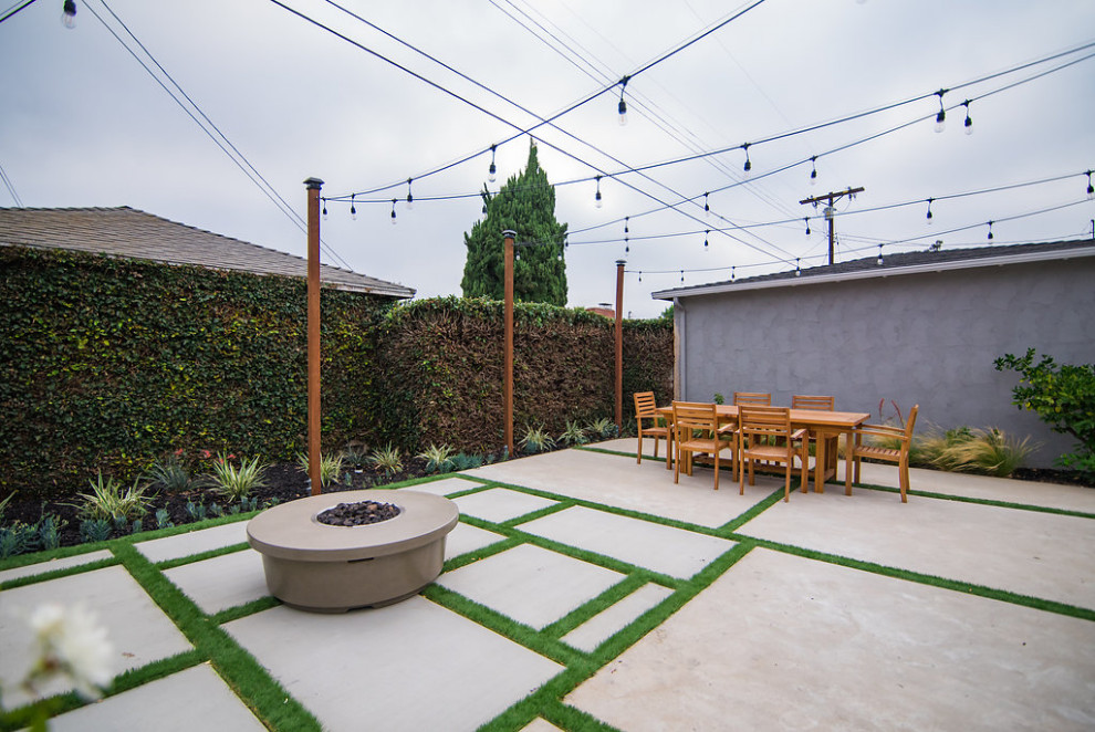 Réalisation d'une petite terrasse arrière design avec un foyer extérieur et des pavés en béton.