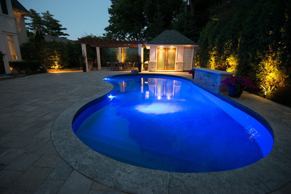 Modelo de piscina con fuente contemporánea de tamaño medio en patio trasero con adoquines de hormigón