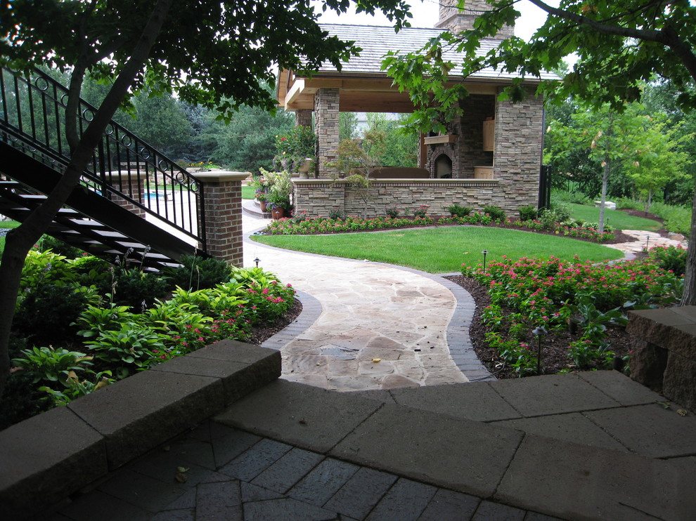 Cette image montre un grand aménagement d'entrée ou allée de jardin arrière traditionnel l'été avec une exposition partiellement ombragée et des pavés en pierre naturelle.