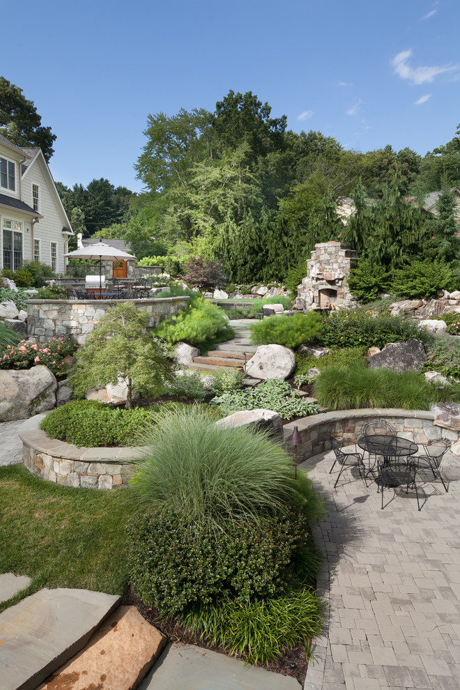 Exemple d'un grand jardin arrière montagne avec un mur de soutènement et des pavés en pierre naturelle.