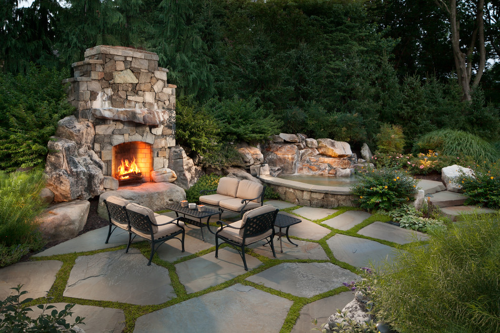 Photo of a large rustic back patio in DC Metro with a fire feature and natural stone paving.