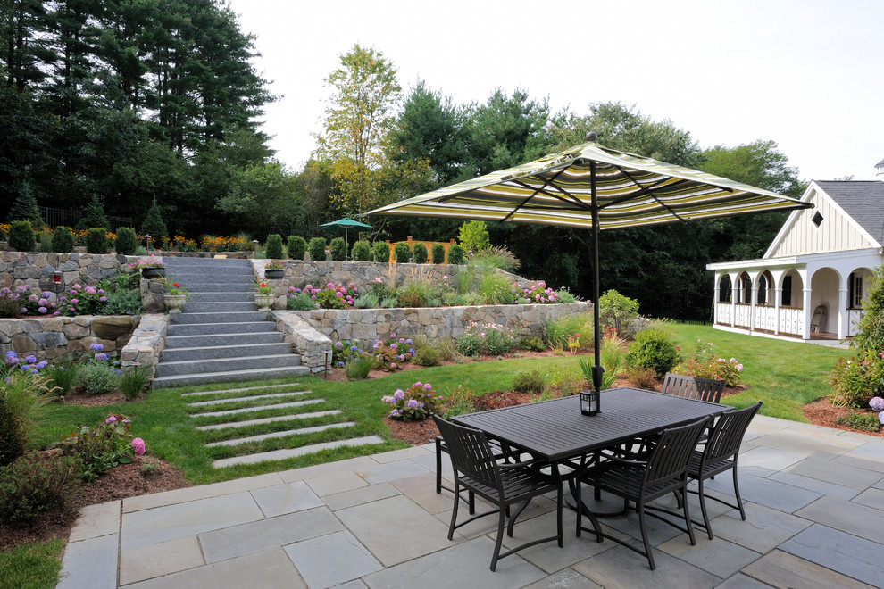 Foto di un ampio giardino design dietro casa con un muro di contenimento e pavimentazioni in pietra naturale