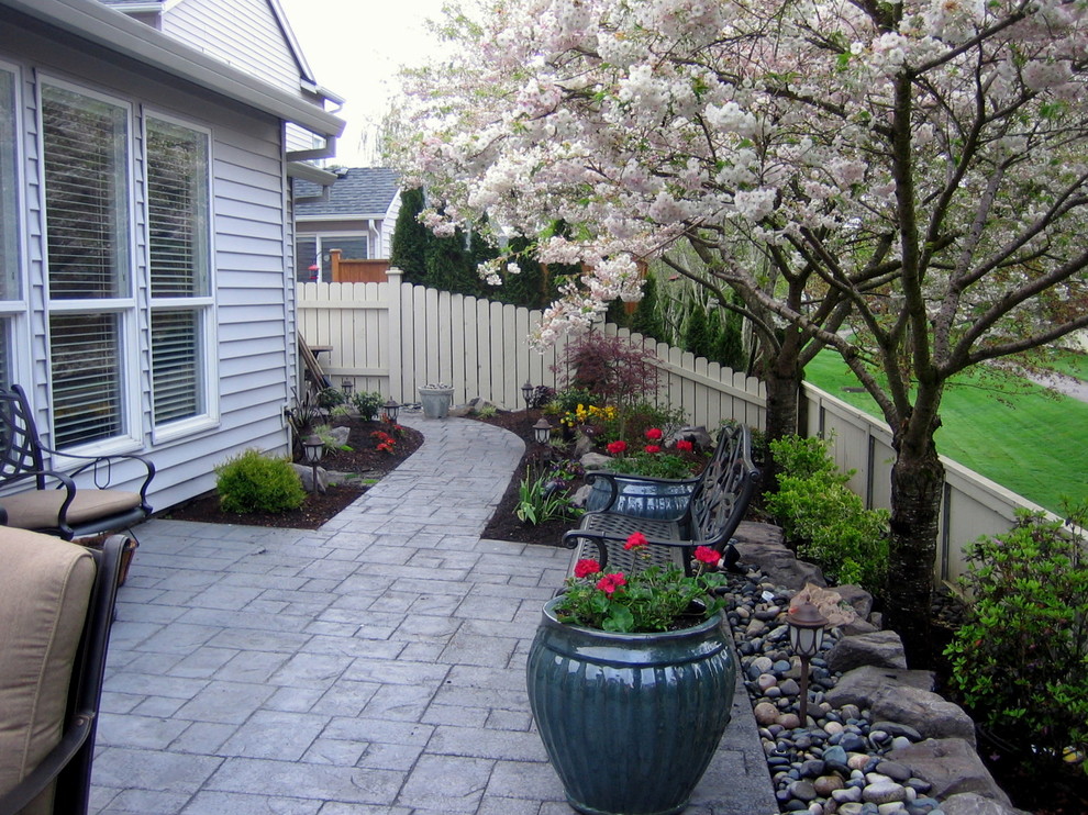 Modelo de jardín clásico pequeño en primavera en patio trasero con muro de contención y exposición parcial al sol