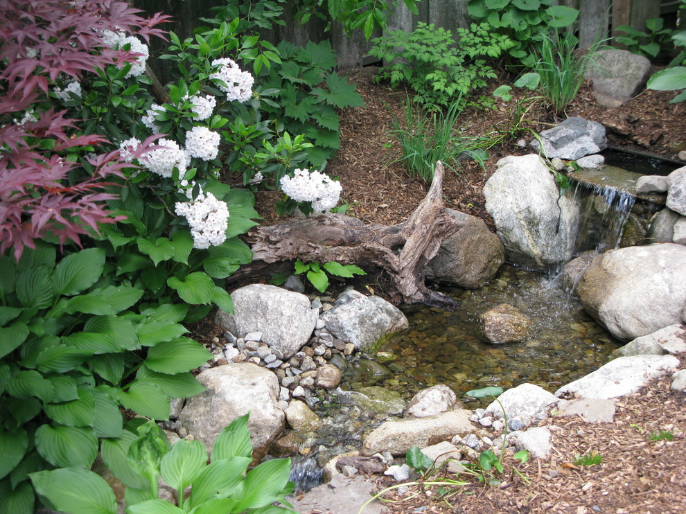 Photo of a bohemian garden for summer in Boston with a water feature and natural stone paving.