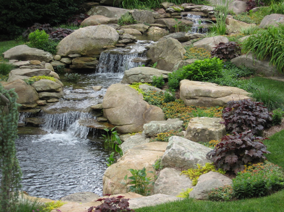 Foto di un grande giardino tradizionale dietro casa con pavimentazioni in pietra naturale e una cascata