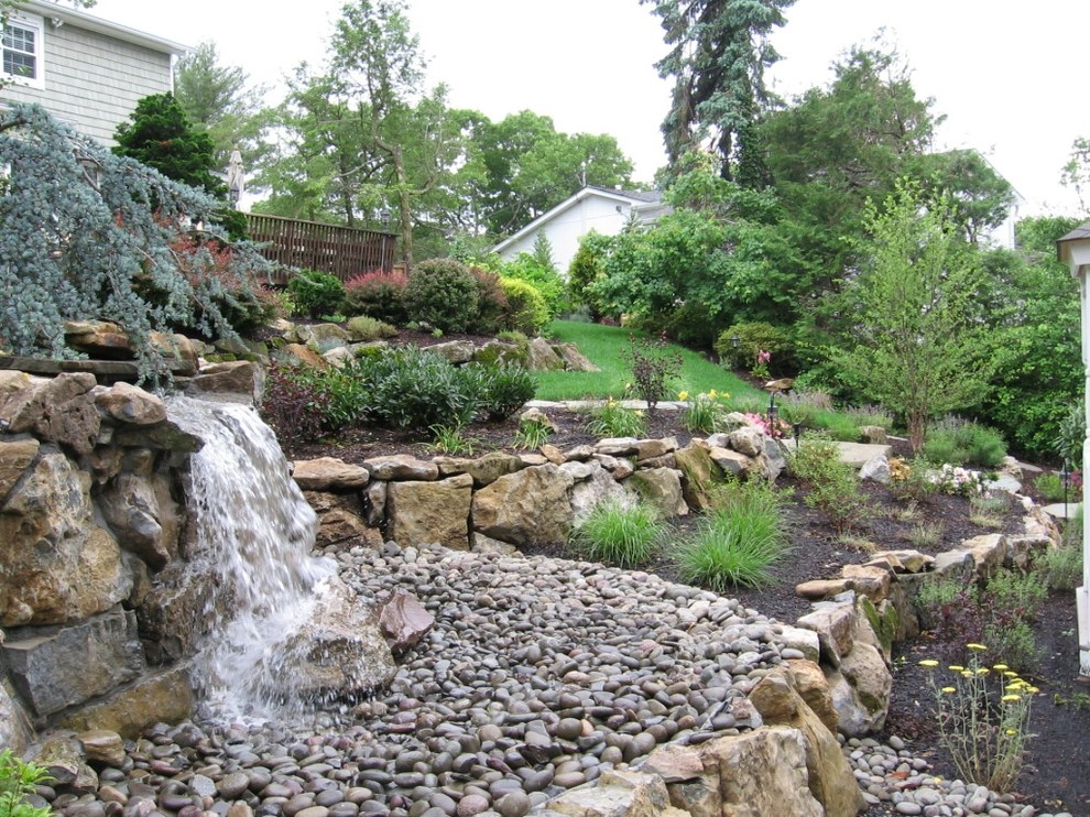 Cette photo montre un jardin arrière exotique avec un mur de soutènement et des pavés en pierre naturelle.