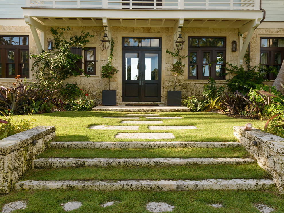 Esempio di un giardino tropicale dietro casa con pavimentazioni in pietra naturale e scale