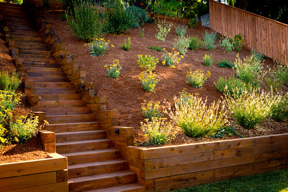 Design ideas for a large drought-tolerant backyard mulch retaining wall landscape in Los Angeles.
