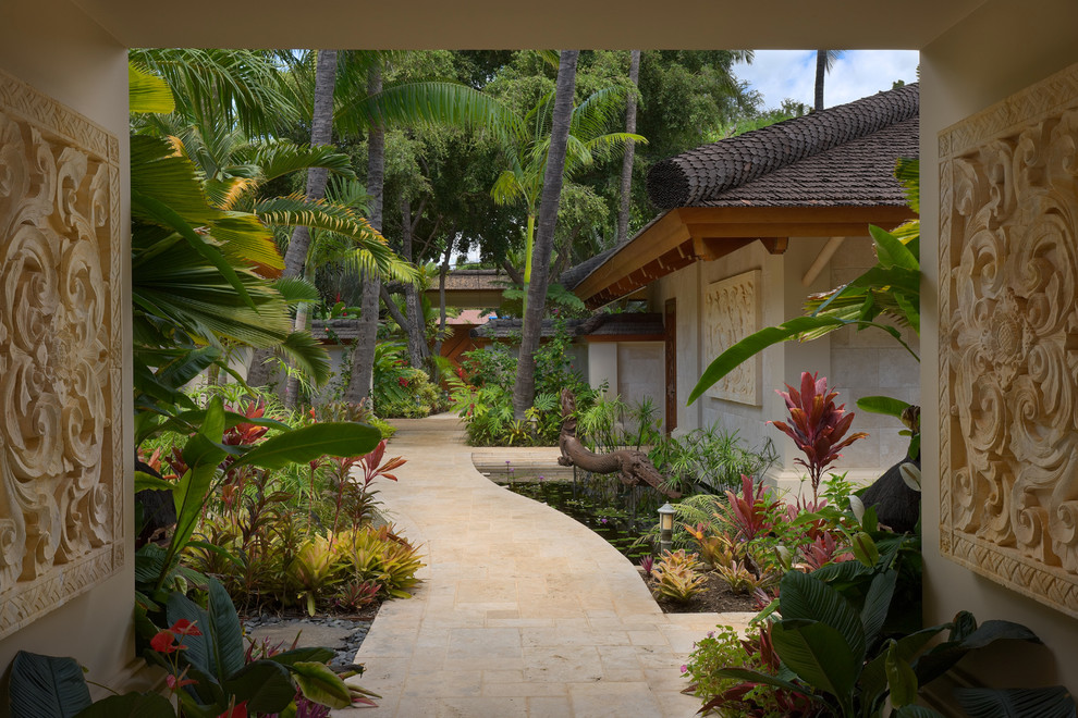 Large world-inspired back partial sun garden in Hawaii with a garden path and natural stone paving.