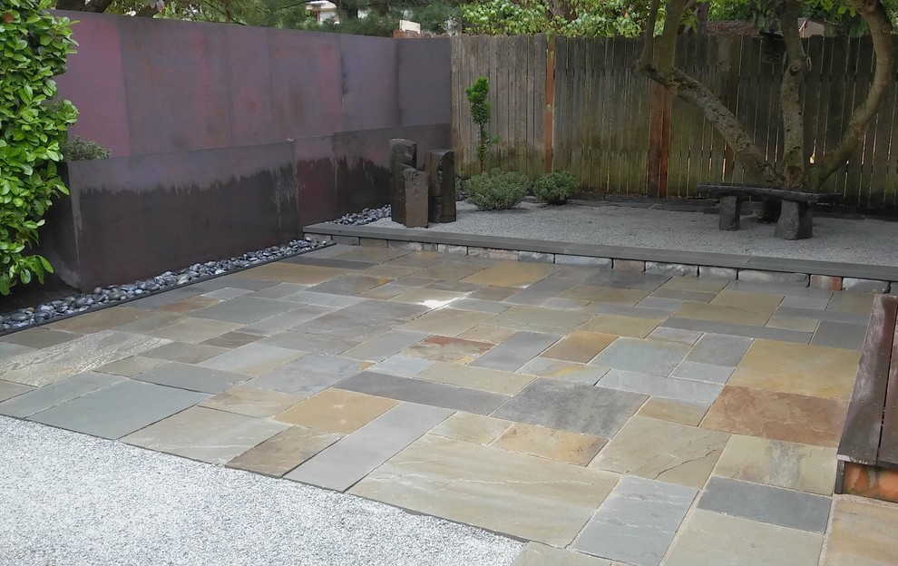 Photo of a mid-sized modern partial sun backyard stone landscaping in Seattle.