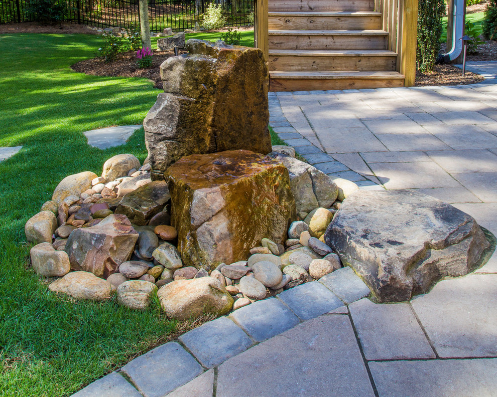 На фото: садовый фонтан на склоне в стиле кантри с покрытием из каменной брусчатки