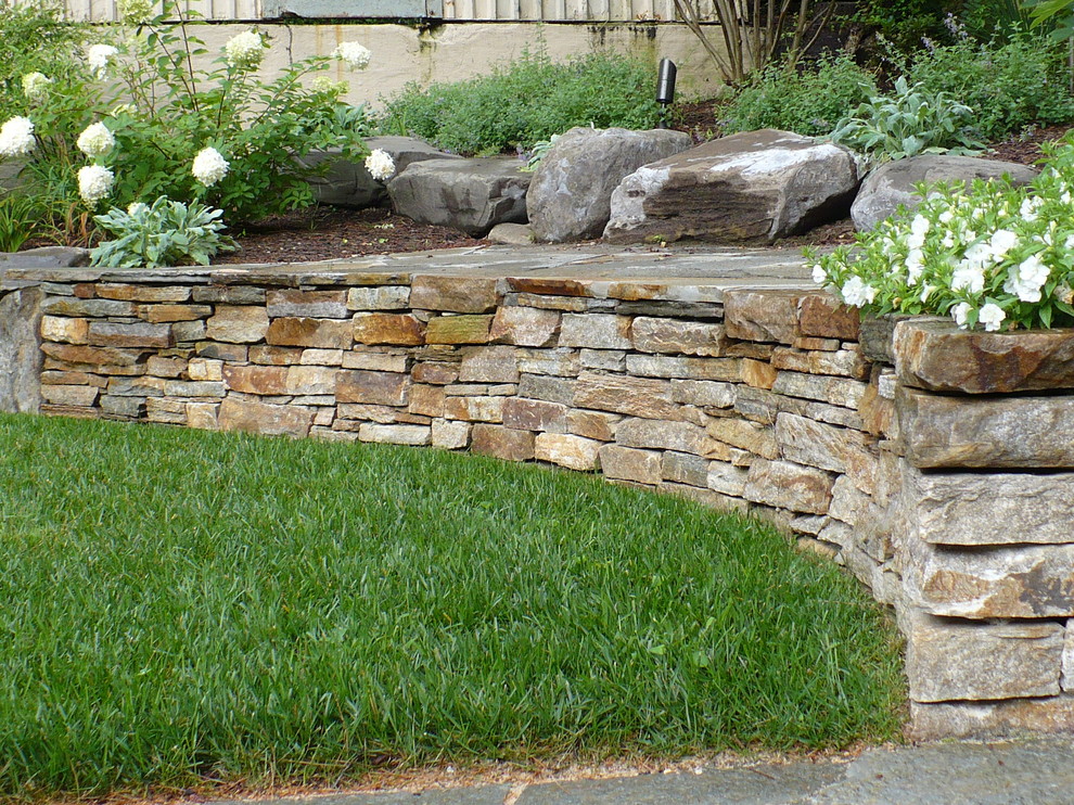 Inspiration pour un jardin arrière chalet de taille moyenne avec un mur de soutènement, une exposition ensoleillée et des pavés en pierre naturelle.