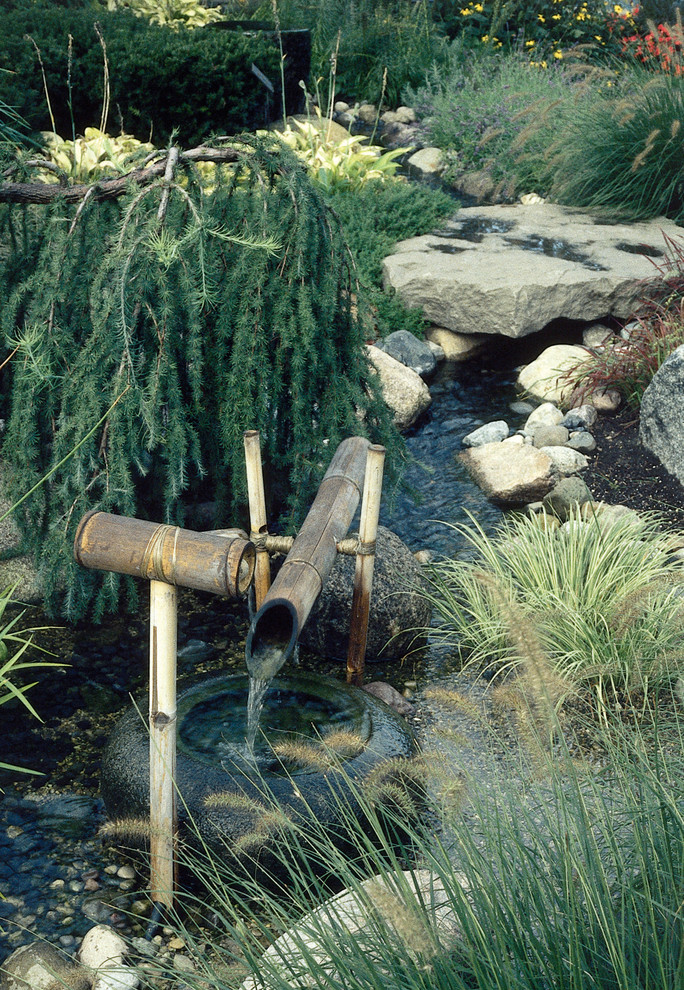 Photo of a mid-sized asian backyard stone water fountain landscape in Detroit.