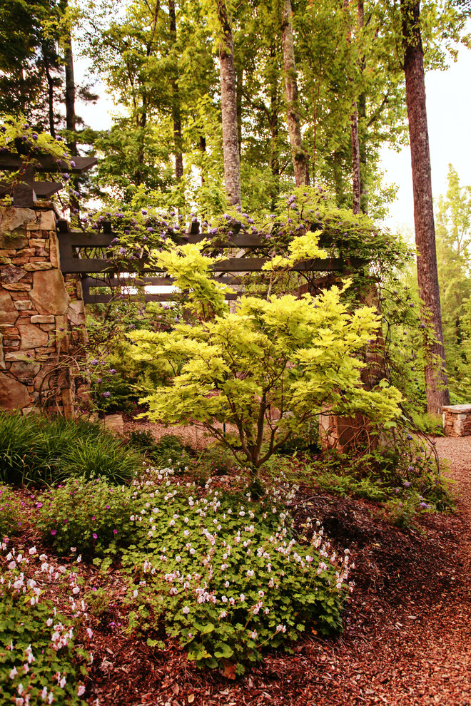 Esempio di un ampio giardino formale classico in ombra in primavera con un pendio, una collina o una riva e ghiaia