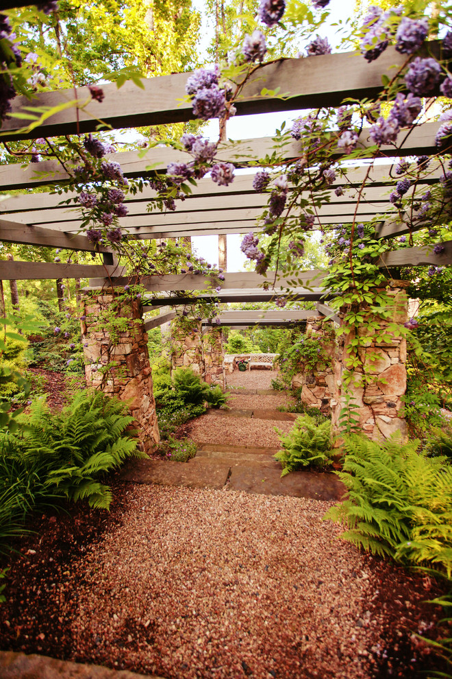 Inspiration för mycket stora klassiska trädgårdar i skuggan i slänt på våren, med en trädgårdsgång och naturstensplattor