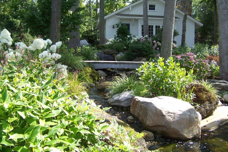 Imagen de jardín clásico extra grande en verano en patio trasero con jardín francés, brasero, exposición total al sol y adoquines de piedra natural