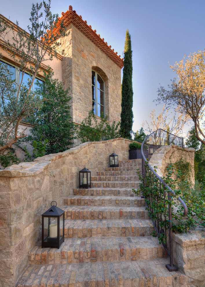 Esempio di un giardino mediterraneo davanti casa con pavimentazioni in mattoni e scale