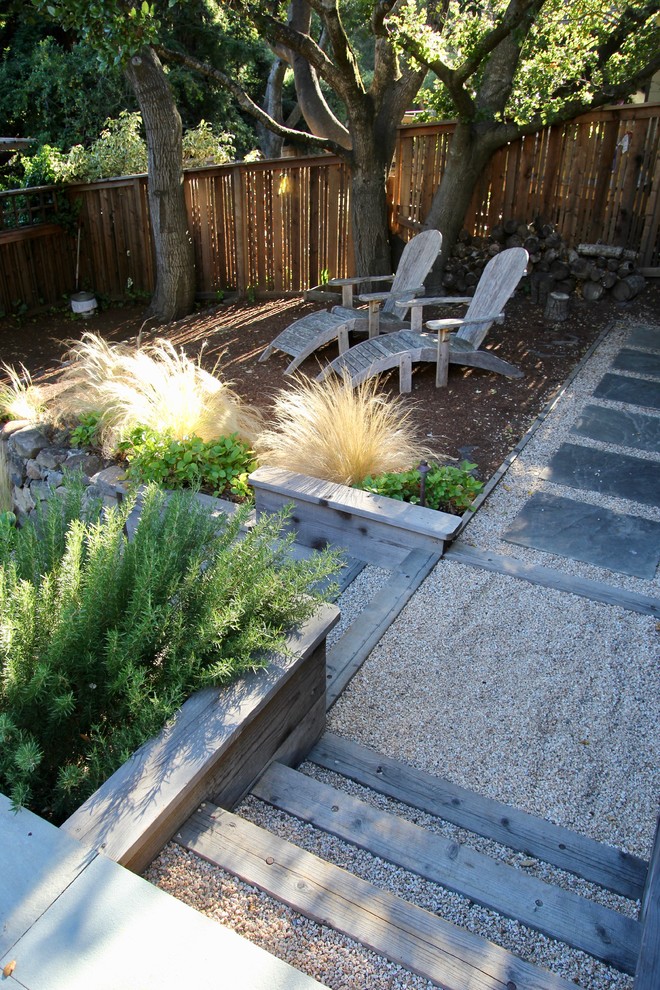 Photo of a medium sized farmhouse back fully shaded garden in San Francisco with a retaining wall and gravel.