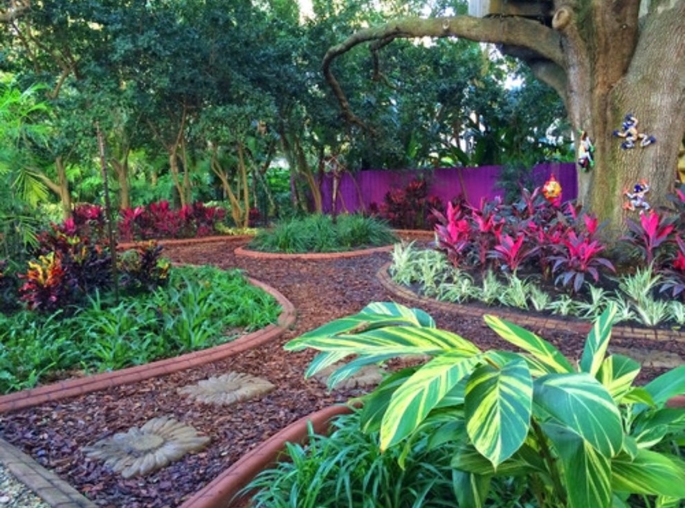 This is an example of a small world-inspired front driveway partial sun garden in Miami with a retaining wall and mulch.