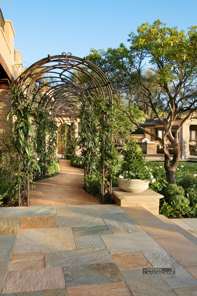 Immagine di un grande giardino formale tradizionale esposto a mezz'ombra nel cortile laterale con un ingresso o sentiero e pavimentazioni in pietra naturale