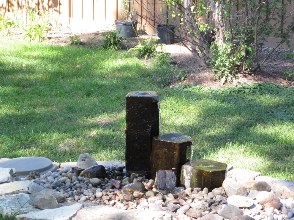Ejemplo de jardín clásico en verano en patio trasero con adoquines de piedra natural
