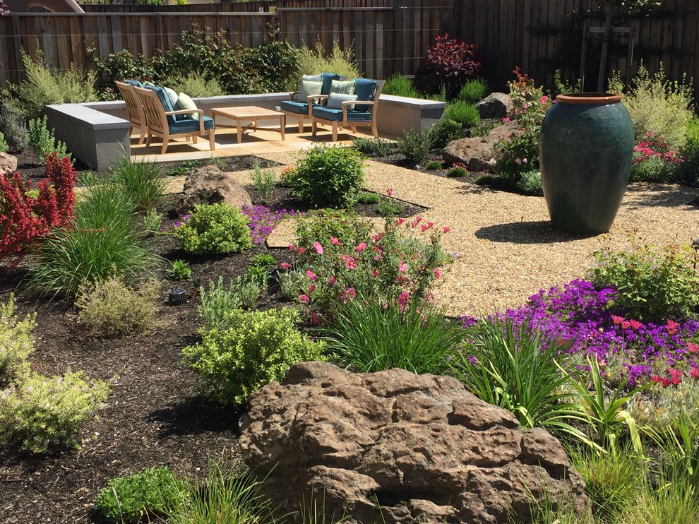 Ejemplo de jardín de secano bohemio de tamaño medio en patio trasero con fuente, exposición total al sol y gravilla