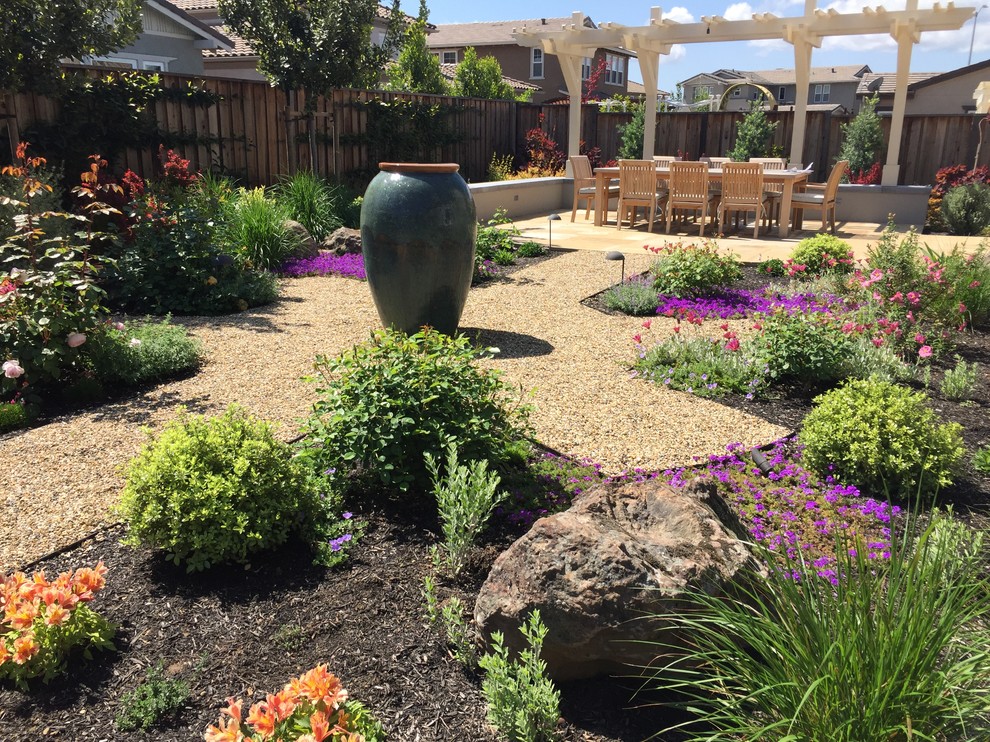 This is an example of a medium sized bohemian back xeriscape full sun garden in San Francisco with a water feature and gravel.