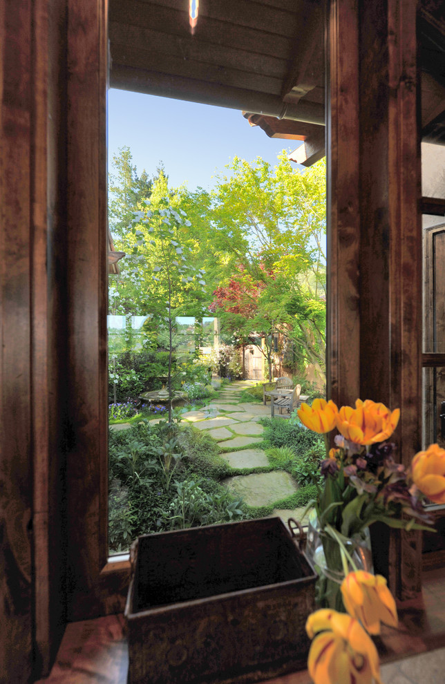 Idee per un ampio giardino formale mediterraneo esposto a mezz'ombra in cortile in primavera con un ingresso o sentiero e pavimentazioni in pietra naturale