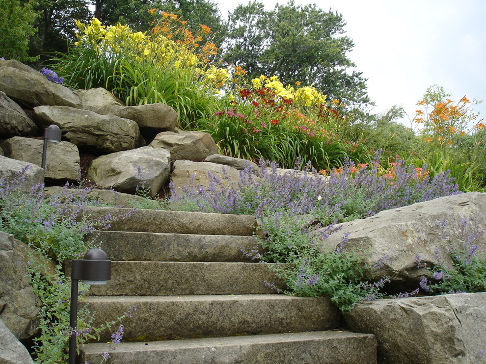 Idee per un grande giardino tradizionale esposto in pieno sole dietro casa in estate con un muro di contenimento e pavimentazioni in pietra naturale