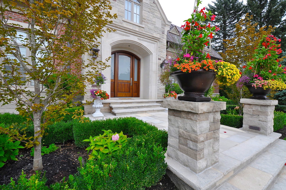 Immagine di un grande giardino formale chic esposto in pieno sole davanti casa con pavimentazioni in pietra naturale e un ingresso o sentiero