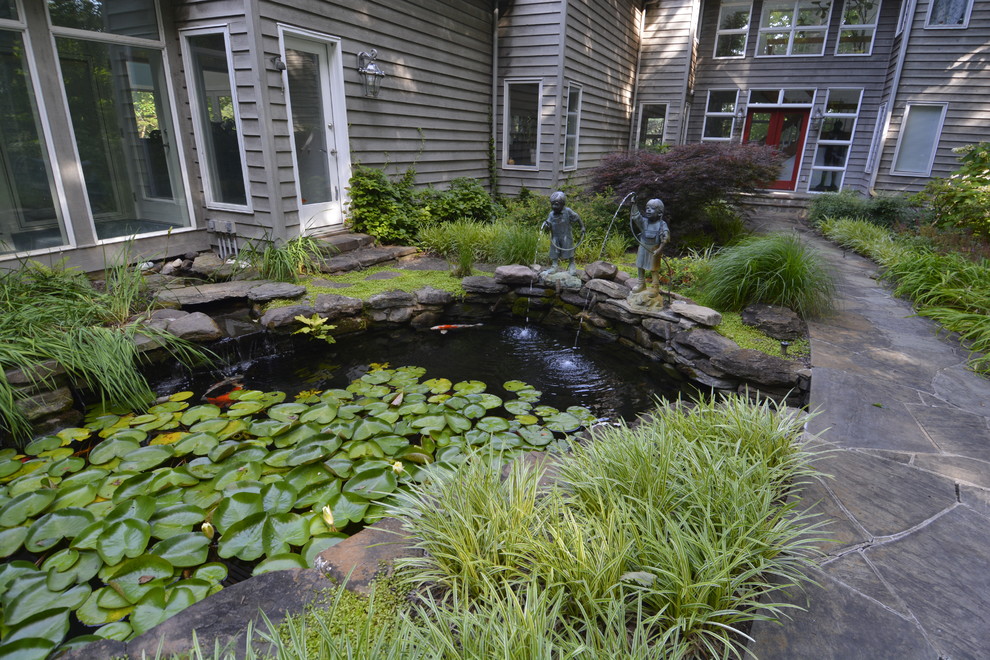 Esempio di un grande laghetto da giardino stile americano in ombra davanti casa in estate con pavimentazioni in pietra naturale
