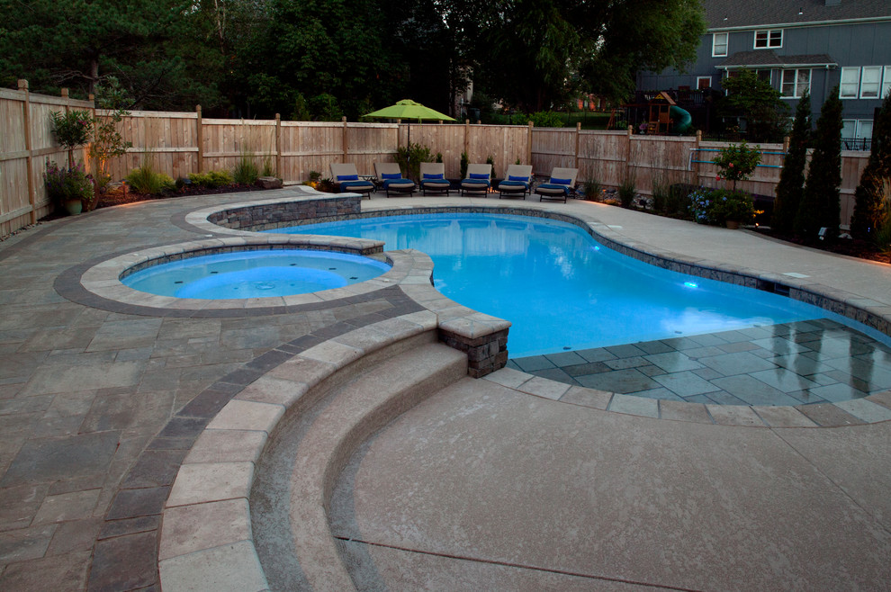 Modelo de piscina clásica en patio trasero con adoquines de hormigón