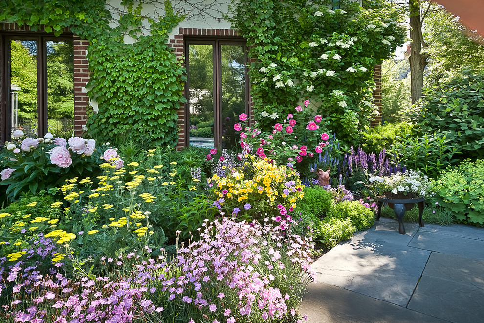 Foto di un piccolo giardino vittoriano esposto in pieno sole dietro casa in estate con pavimentazioni in pietra naturale